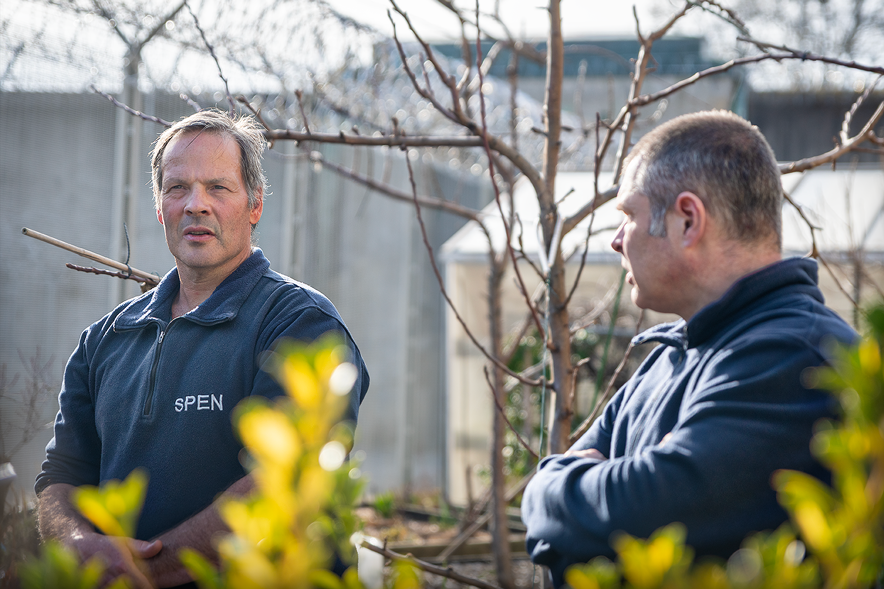 Deux hommes discutent dans un jardin