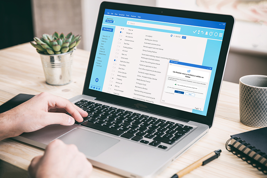 Un écran de laptop ouvert. Une petite fenêtre s'ouvre avec le message fabriqué qui disait "Léa Rossier vous a invité(e) à valider un fichier"