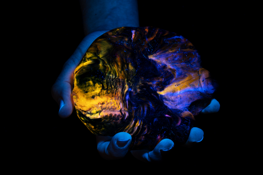 L'objet vu dans la lumière infrarouge, entre deux mains. Il révèle des couleurs jaunâtres en transparence.