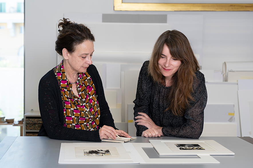 Les deux femmes assises à un bureau, examinent des dessins de Vallotton.