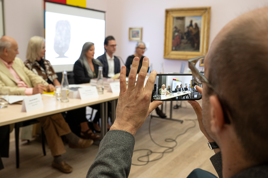Michel Vust vu de derrière, alors qu'il prend une photo des personnes qui parlent lors de la conférence de presse.