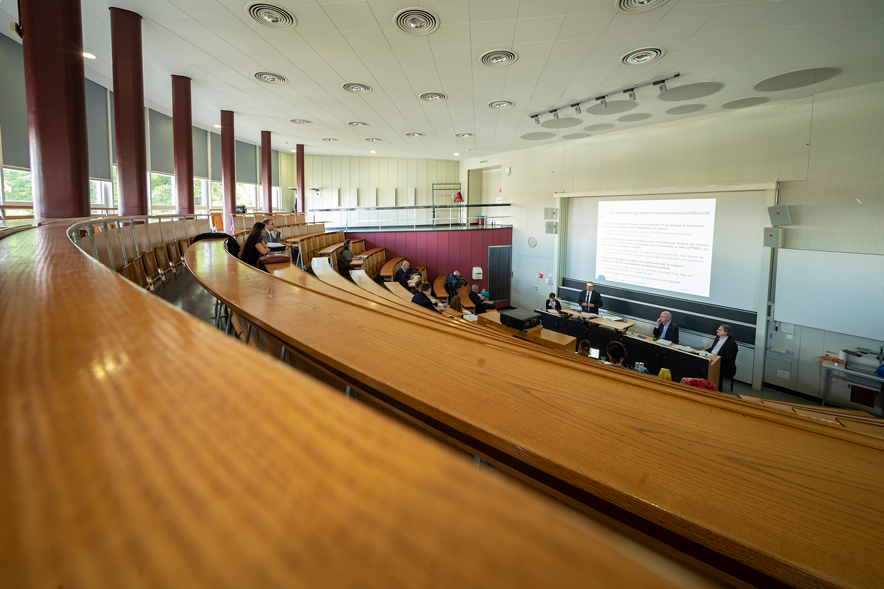 Le grand amphithéâtre, avec quelques personnes assises, et des personnes au pied des bancs, lors d'une conférence.