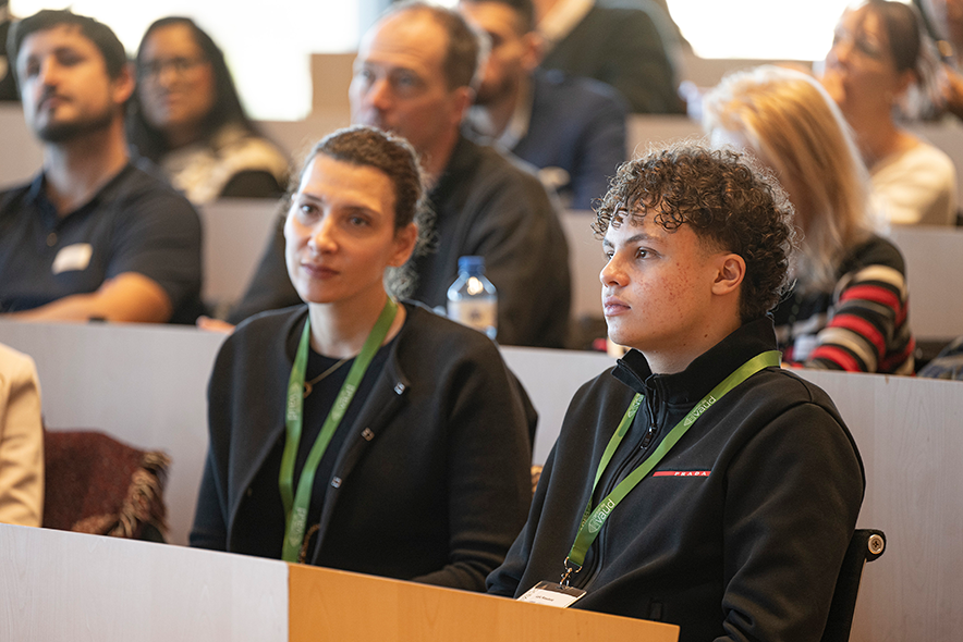 Les deux personnages assis dans la salle du Grand Conseil, portent des sautoirs verts en tissu avec leur badge de la journée.
