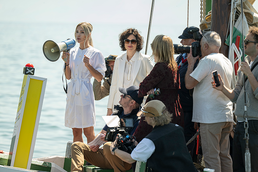 les personnes à bord de la barque La Demoiselle. Madame Rousse parle dans un mégaphone.