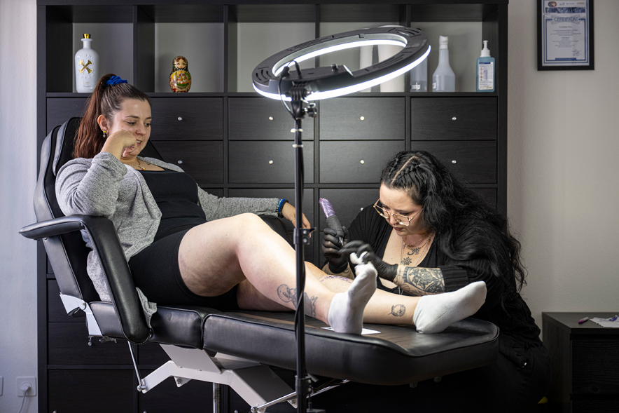 Une femme se fait tatouer sur un fauteuil de tatouage