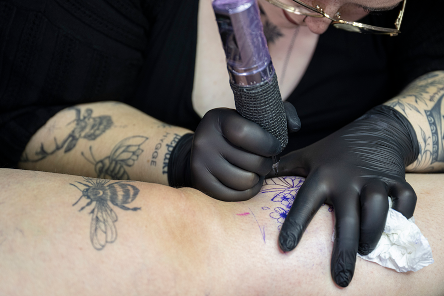 Lorianne Goy tatoue un motif sur une jambe